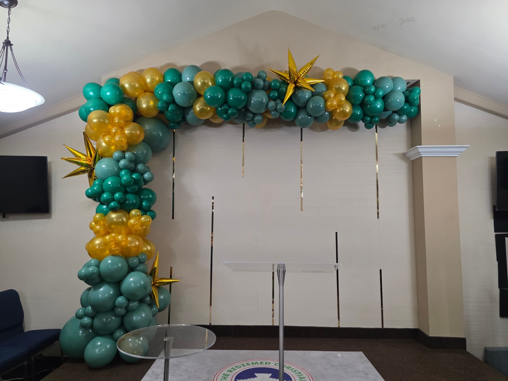 Emerald and gold balloon garland arch with gold starburst balloons